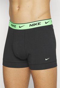 Schwarze Baumwoll-Boxershorts mit einem neon-grünen Nike-Logo-Bund. Sie bieten eine enge Passform und eine weiche Textur, mit kontrastierenden Nähten.