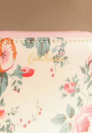 Lillatrükiga kangast kott roosa lukuga, millel on pastelsed roosid ja rohelised lehed ning kullast "Cath Kidston" logo trükitud peamise serva lähedale.