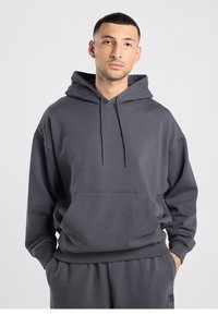 Grijze katoenen hoodie met een grote voorzak, capuchon met trekkoord en geribbelde boorden. Heeft een ontspannen pasvorm en een gladde textuur.