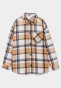 Camisa de cuadros en beige, blanco y negro. Confeccionada en tela de franela, presenta un cierre delantero de botones, cuello y un único bolsillo en el pecho con un patrón a juego.