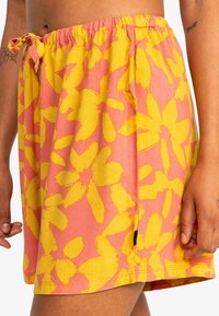 Falda de patrón floral en rosa y amarillo, hecha de una tela ligera, con cintura elástica y abertura lateral, adecuada para uso casual.
