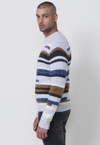 Gebreide trui in variërende strepen van grijs, bruin, blauw en zwart. Zacht, gestructureerd materiaal met een ronde hals en ribgebreide manchetten.