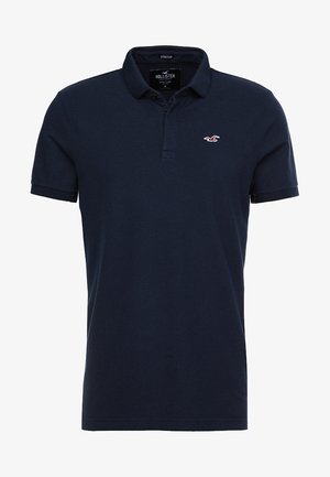 Marineblaues kurzärmliges Poloshirt mit Kragen, Knopfleiste mit zwei Knöpfen und kleinem weißem Möwenlogo auf der linken Brust.
