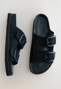 Chanclas deslizables en negro y azul marino con doble correa ajustable con hebillas, suave textura de ante y suela de goma moldeada.