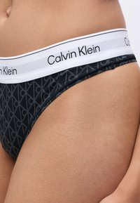 Svart og gråmønstret truse med hvit midje som har "Calvin Klein"-logo i svart. Mykt tekstilmateriale og glatt tekstur.
