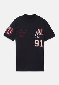 T-shirt in cotone nero con grafiche ricamate, tra cui "AX" e "91" in bianco e rosso, e un badge con "A/X 91" sulla manica.