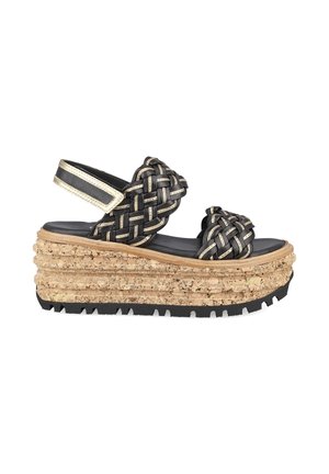 Sandale à plateforme avec semelle épaisse en liège, brides tissées noires et beiges, et bride de cheville réglable avec fermeture Velcro.