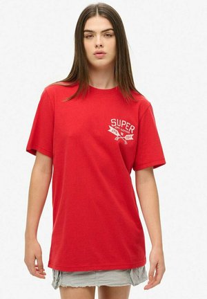 Rotes Baumwoll-T-Shirt mit kurzen Ärmeln, einem Rundhalsausschnitt und einem weißen Drucklogo auf der linken Brust. Glatte Textur, entspannter Schnitt.