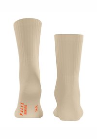 Beige gerippte Knöchelsocken mit FALKE-Branding in Orange. Weicher Stoff, der für Komfort ausgelegt ist, mit einem mittelhohen Schnitt und subtilen Details.