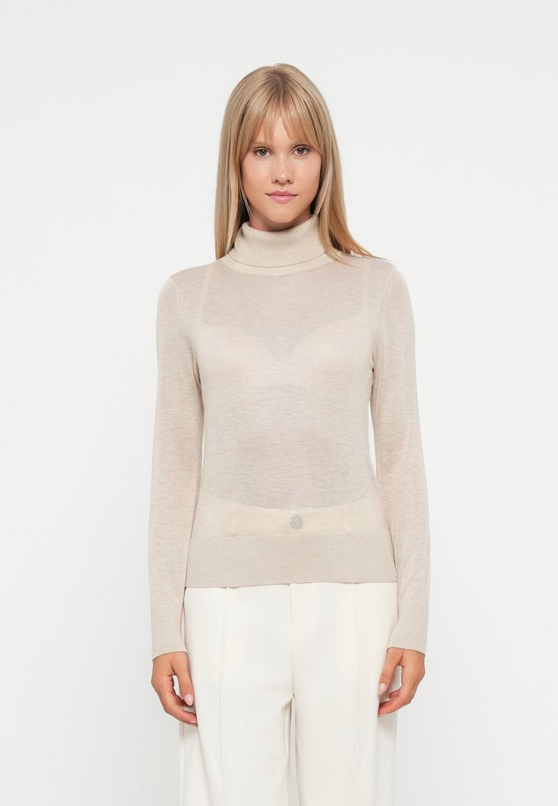Pull en col roulé beige en tissu léger et transparent. Il dispose de manches longues et de poignets côtelés, avec une silhouette ajustée et une texture subtile.
