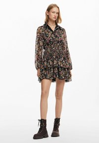 Blommönstrad svart klänning med krage, långa ärmar, elastisk midja och lager på lager kjol. Matchad med mörka ankboots.