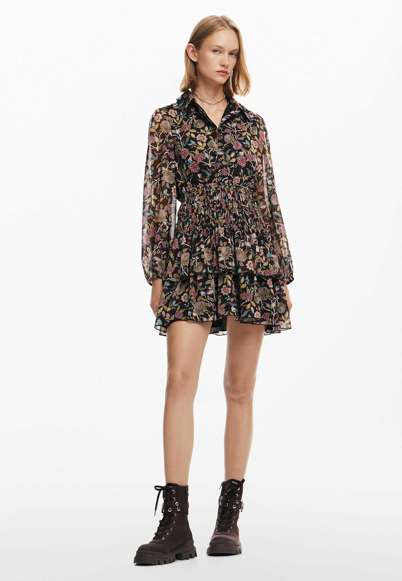 Blommönstrad svart klänning med krage, långa ärmar, elastisk midja och lager på lager kjol. Matchad med mörka ankboots.