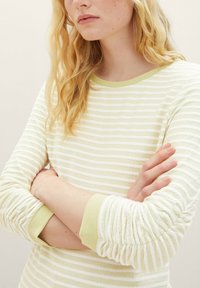 Hellgrünes und weiß gestreiftes Langarmshirt mit gerippten Bündchen. Der Stoff hat ein strukturiertes Muster und zeichnet sich durch einen lockeren Schnitt aus.