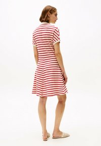 Gestreiftes Kleid in Creme mit roten horizontalen Streifen, kurzen Ärmeln und einem ausgestellten Rock. Verfügt über einen Kragen und ein rückseitiges Nahtdetail.