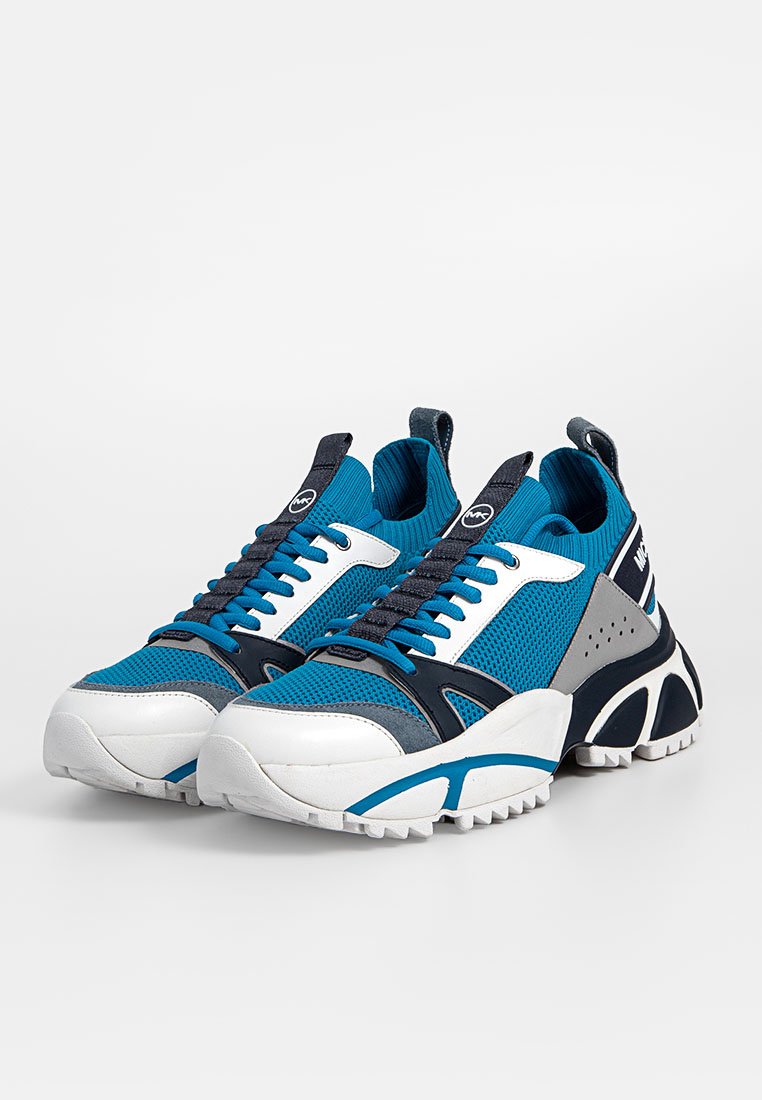 Blaue und graue Sportschuhe aus Mesh-Gewebe, mit weißen Akzenten, dicker Sohle, runder Zehenpartie und ausgeprägtem Profil. Schnürsenkel in Dunkelblau.