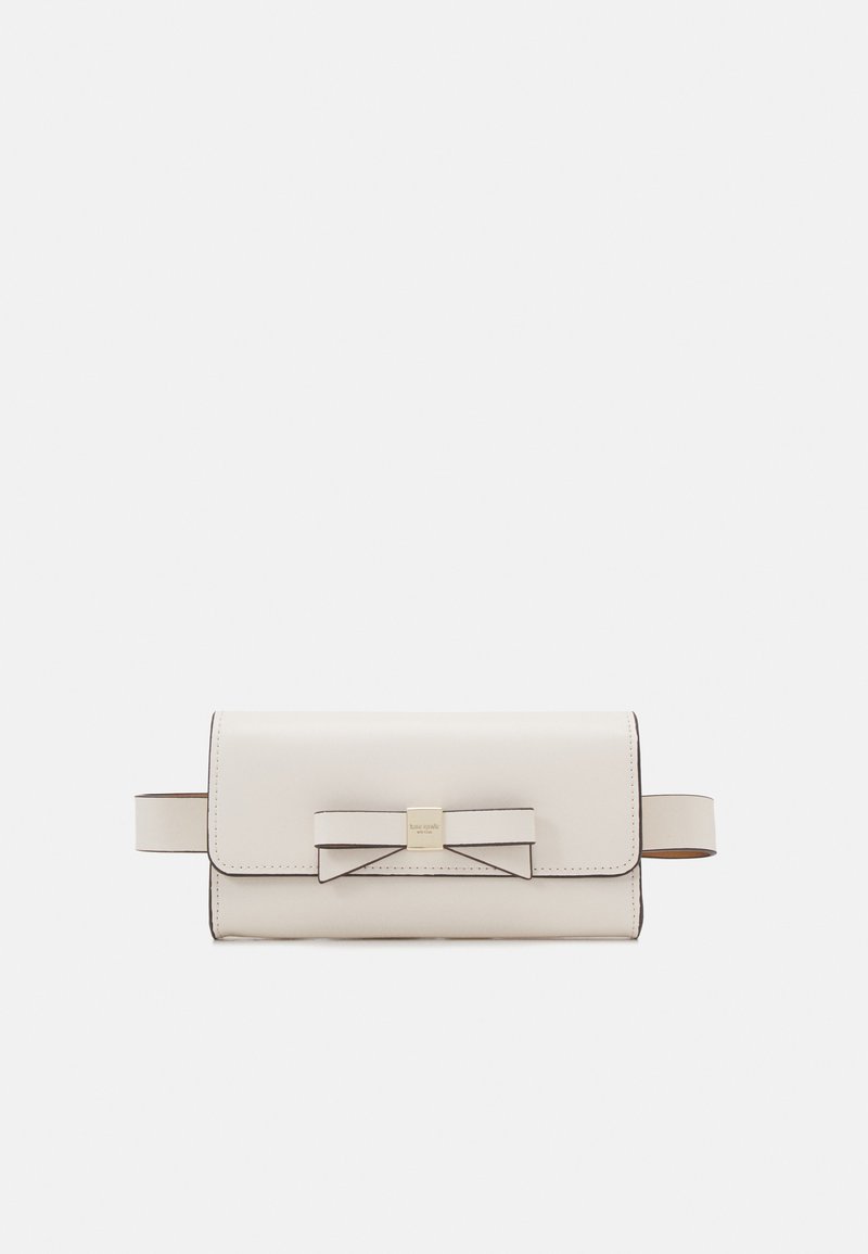 Light beige leather bag featuring a bow accent, flap closure, and a gold-tone hardware logo. Includes two side straps. Smooth texture.