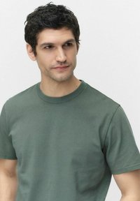 Grön bomull t-shirt med rund hals, korta ärmar och en slät yta. Har diskreta sömnadsdetaljer och en avslappnad passform.