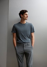 Grijze T-shirt met een ronde hals, gecombineerd met grijze broek. De stof lijkt zacht, met een gladde afwerking en een ontspannen pasvorm.