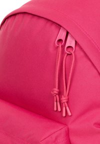 Zaino rosa con esterno in nylon liscio, doppia zip rosa e coulisse in stile paracord con dettagli annodati.