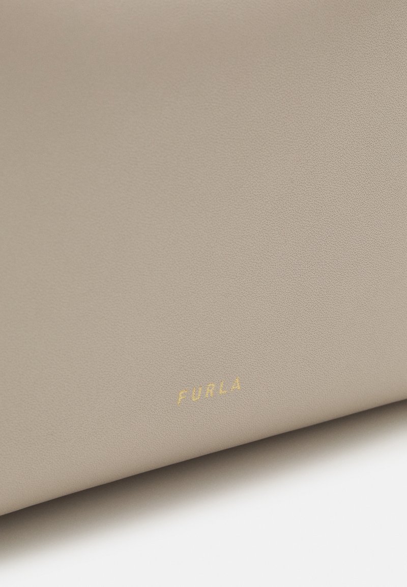 Portafoglio in pelle beige con finitura текстurizzata e logo "Furla" dorato. Presenta un design minimalista e una forma rettangolare compatta.