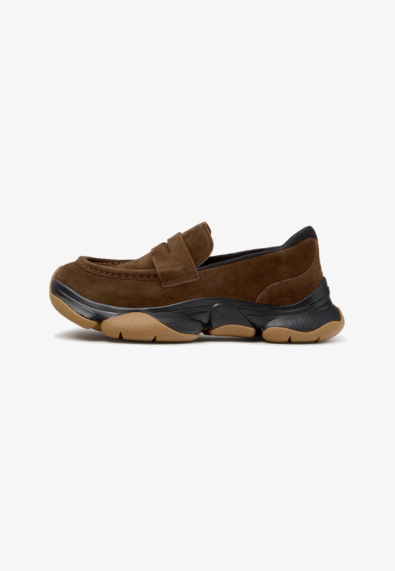 Chaussure en daim marron à enfiler avec une semelle en caoutchouc épaisse noire et beige et un détail de bride sur le dessus, vue de côté.
