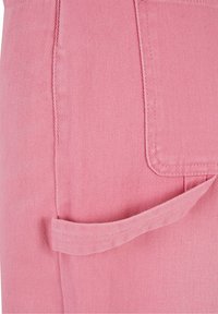 Tela de mezclilla rosa con una textura de canalé diagonal, que presenta un bolsillo lateral con un detalle de solapa y acentos cosidos.