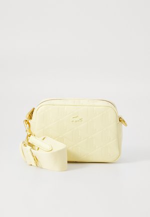 Bolsa de polietileno amarilla con un patrón geométrico, cierre de cremallera, herrajes dorados y una correa desmontable color crema. Forma rectangular.