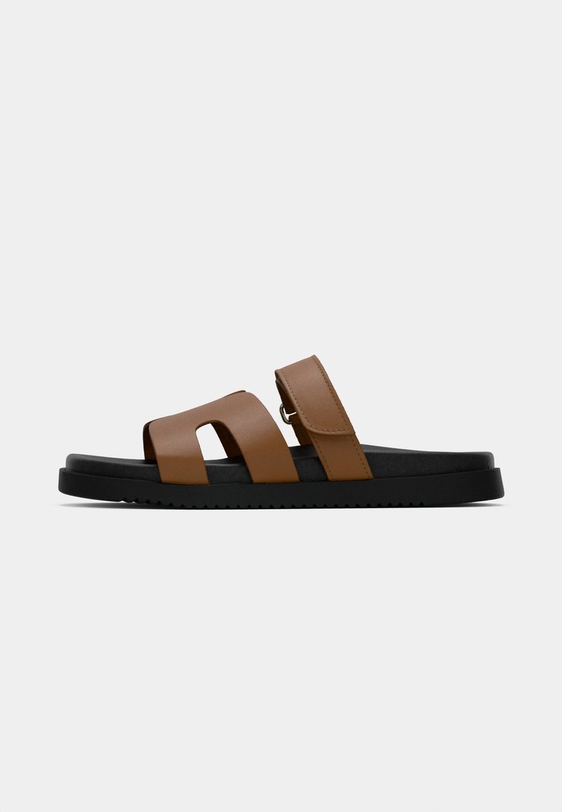Sandales en cuir brun avec deux larges sangles, dont une dotée d'une boucle, sur une semelle en caoutchouc noire. Texture lisse et design ouvert pour une bonne respirabilité.