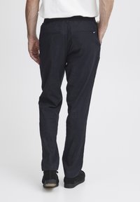 Navy blue trousers with a relaxed fit, elastic waistband, and back pockets. The fabric has a soft texture with subtle sheen.