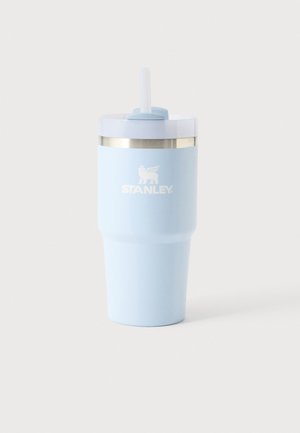 Gobelet isolant Stanley bleu clair avec un couvercle blanc et une paille transparente sur un fond clair uni.