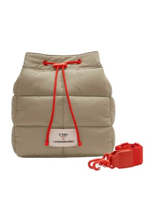 Sac seau beige matelassé avec fermeture à cordon rouge, écusson logo sur le devant, et bandoulière rouge amovible posée à côté.