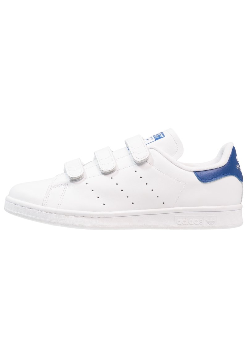 Baskets basses blanches avec trois bandes Velcro, détails perforés sur les côtés et languette de talon bleue avec logo.