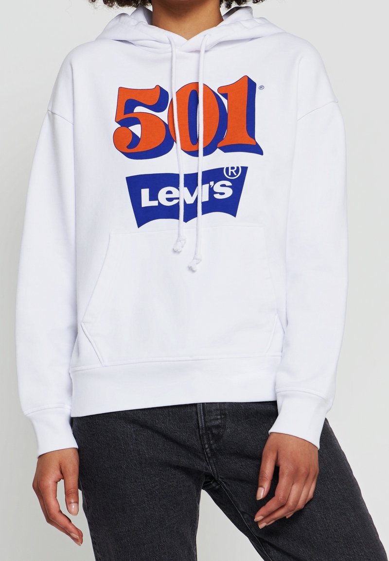 Vit hoodie med en stor röd och blå "501" grafisk design och "Levi's" logotyp på framsidan. Har en framficka och snörning i huvan.