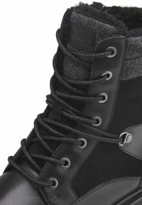Botas de invierno negras con cordones, que presentan una base de cuero suave, un cuello de tela de lana, herrajes plateados y cordones texturizados.