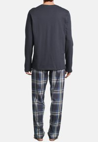 Chemise en coton bleu marine à manches longues associé à un pantalon de pyjama en flanelle à carreaux bleu, gris et blanc. Coupe décontractée, texture douce et poignets côtelés.