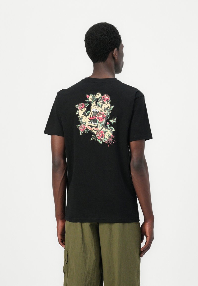 Black cotton t-shirt with short sleeves, featuring a colorful graphic design of a skull and roses on the back. Simple crew neckline.