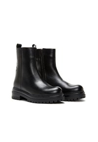 Paire de bottines en cuir noir avec semelles épaisses à rainures et fermetures éclair latérales, affichée sur fond blanc.