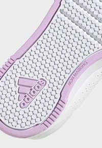 Bílá podešev tenisky s texturovaným povrchem a růžovým akcentem. Obsahuje kruhové gripy a logo "adidas" s tištěným detailem "NON MARKING".