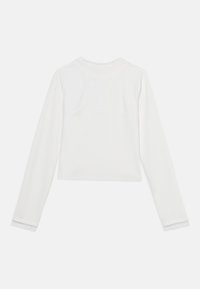 Λευκό τοπ με μακριά μανίκια και στρογγυλή λαιμόκοψη, εφαρμοστή σχεδίαση και λεπτομέρειες χωρίς ραφές στους ώμους. Απαλή ύφανση με ελάχιστες ραφές.