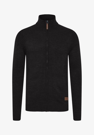 Mustast tõmblukuga kardigan tekstureeritud kudumifabricist. Omab kõrget kaelust ning soonikuid mansetis ja allääres. Sisaldab väikest nahast brändipatchi.