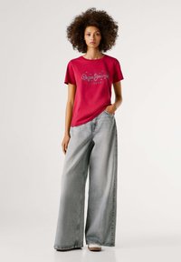 Rode katoenen t-shirt met logodetail, gecombineerd met wijde vervaagde grijze denimjeans. Minimalistisch ontwerp en ontspannen pasvorm.