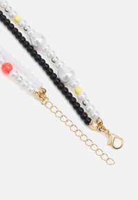 Colar de contas com contas pretas, brancas, transparentes, amarelas e vermelhas; com acessórios em dourado, fecho de lagosta e extensor de corrente.