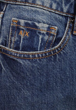Vaqueros de mezclilla azul oscuro con costuras naranjas y un pequeño bolsillo delantero con las letras A|X bordadas en hilo naranja.