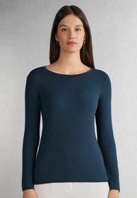 Langarmshirt in Dunkelblau, aus glattem Stoff. Merkmale einen runden Ausschnitt und eine figurbetonte Passform mit dezenten Nahtdetails.