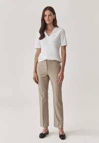 Top bianco a maniche corte con scollo a V abbinato a pantaloni beige a righe sottili e ballerine nere; design elegante e aderente, tessuto morbido.