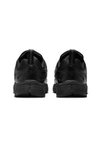 Ζεύγος μαύρων αθλητικών παπουτσιών που φαίνονται από πίσω, με  υφασμένους πάτους, θηλιές και λεπτομέρειες από πλέγμα πάνω στα τμήματα του παπουτσιού.