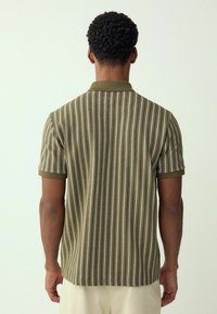 Gestreepte polo in olijfgroen met witte en lichtbeige verticale strepen. Korte mouwen en een effen kraag. Textuurstof.