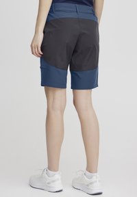 Shorts de sport bleus et noirs, composés d'un mélange de tissus texturés et lisses. Longueur mi-cuisse, avec des détails de panneaux latéraux et une taille ajustée.