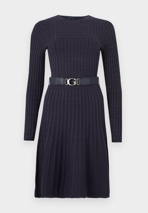 Πλεκτό φόρεμα σε σκούρο ναυτικό μπλε με μακριά μανίκια, υφασμένο διαμάντι μοτίβο, εφαρμοστό μπούστο και φαρδιά μέση με ζώνη που φέρει ασημένια πόρπη με λογότυπο.