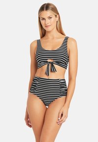 Costume da bagno a due pezzi a righe bianche e nere, caratterizzato da un top corto con un nodo frontale e un pantaloncino a vita alta con dettagli arricciati.